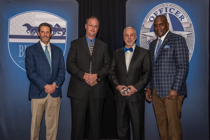 An image of four gentlemen standing in front of the event signage for the Irving Police Dept.
